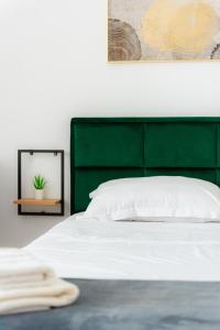 a white bed with a green headboard and a mirror at Premium Studio next to National Arena & Park in Bucharest