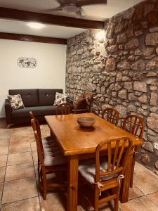 una mesa de madera y sillas en una habitación con una pared de piedra en Alojamientos Mestanza, en Baños de la Encina