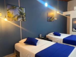 twee bedden in een kamer met blauwe muren bij Casa Hotel La Palmera Apartadó in Apartadó