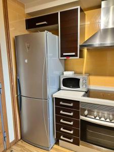 uma cozinha com um frigorífico de aço inoxidável e um micro-ondas em Lotf alquiler valencia em Burjassot