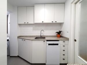 uma cozinha branca com um lavatório e armários brancos em Acojedor piso cerca del metro em Cornellà de Llobregat