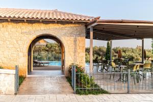 a stone building with an archway and tables and chairs at Olympia Zervea Studios with Pool - Apartment in Kardamili