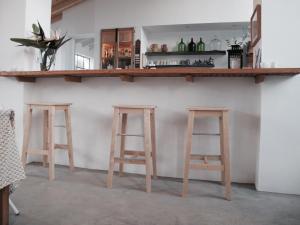 a bar with three wooden stools in a room at Tres Marias in Vila Nova de Milfontes