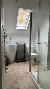 a bathroom with a tub and a toilet and a skylight at Aldo's 2 Bedroom Townhouse London N1 in London