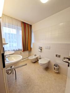 a bathroom with two sinks and a toilet and a window at Hotel Kaiser in Berlin