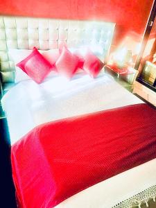 a bed with red and white pillows on it at Appartement luxueux Centre Agadir in Agadir