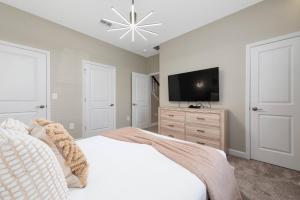 une chambre avec un lit blanc et une télévision à écran plat dans l'établissement 4 bedrooms house with pool, à Kissimmee