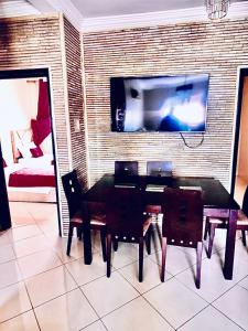 stół jadalny z krzesłami i telewizor na ceglanej ścianie w obiekcie Appartement luxueux Centre Agadir w mieście Agadir