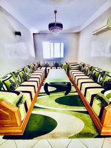 Appartement luxueux Centre Agadir في أغادير: قاعة اجتماعات مع طاولة وكراسي على سجادة خضراء