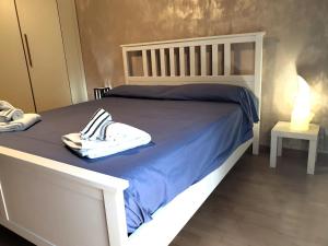 a white bed with blue sheets and white shoes on it at Euforbia House in Lido di Ostia