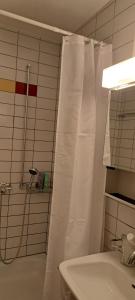 baño con ducha con cortina blanca en goldenes 1-Zimmer-Appartement Kreuzlingen, en Kreuzlingen