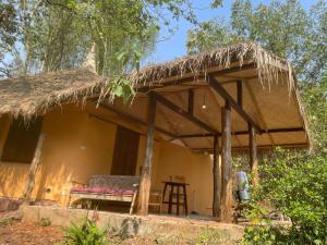 a small house with a thatched roof and a table at Chiang Dao Roundhouses in Chiang Dao