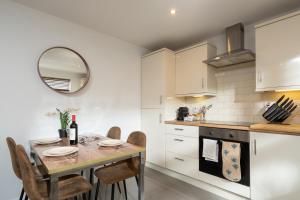 een keuken met een tafel met stoelen en een spiegel bij Cosy Modern City Centre 2 Bed Apartment in Belfast