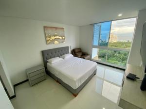1 dormitorio con cama y ventana grande en Apartamentos Ocean Club - Cerca al Mar by SOHO, en Santa Marta