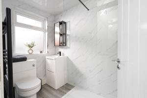 a white bathroom with a toilet and a window at City Vibe Haven - Modern 2 Bed Apartment with High Speed WI-FI in Belfast