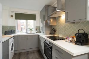 a kitchen with white cabinets and a stove top oven at City Vibe Haven - Modern 2 Bed Apartment with High Speed WI-FI in Belfast