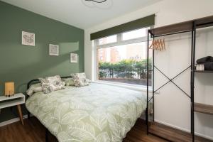 a bedroom with a bed and a large window at City Vibe Haven - Modern 2 Bed Apartment with High Speed WI-FI in Belfast