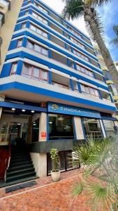 ein blaues Gebäude mit einer Palme davor in der Unterkunft Apartamentos Tinoca in Las Palmas de Gran Canaria