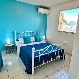 Dormitorio azul con cama y ventana en Villa KAZ A ZOT en Port-Louis