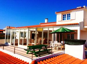 Casa con terraza con sombrilla verde en FreeSurfCamp & Hostel, en Peniche