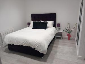 a bedroom with a large bed with white sheets and black pillows at Riverside Annex at Ashbank in Penrith