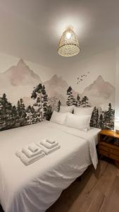 a bedroom with a white bed with mountains on the wall at Le Chalet de la Plage in Sévrier