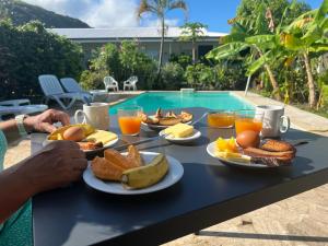 a table topped with plates of food next to a pool at Pension De La Plage in Punaauia