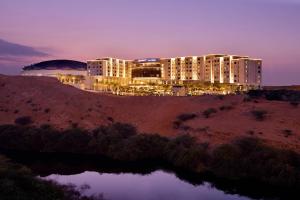 JW Marriott Hotel Muscat في مسقط: مبنى كبير على قمة تل في الليل