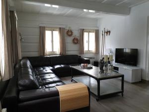 een woonkamer met een zwarte leren bank en een tafel bij Jizera Cottage in Rokytnice nad Jizerou