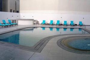 a large swimming pool with blue chairs in a building at City center area seef Mall in Sanābis