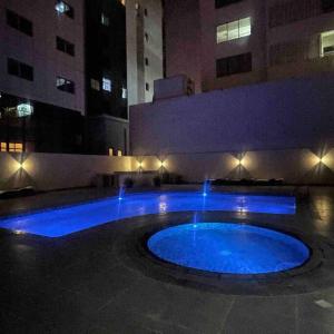 a blue pool in the middle of a building at night at City center area seef Mall in Sanābis