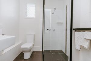 a white bathroom with a toilet and a shower at Yeppoon Surfside Motel in Yeppoon