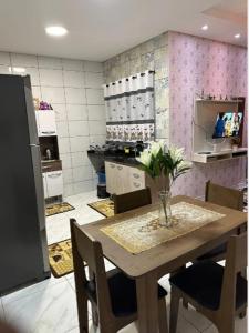 Una cocina con una mesa con un jarrón de flores encima. en Linda casa completa confortável, en Foz do Iguaçu