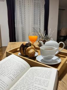 een dienblad met een boek en een kopje koffie en een bord brood bij Stan na dan Kozarska Dubica in Bosanska Dubica