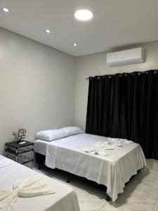 two beds in a room with black curtains at Linda casa completa confortável in Foz do Iguaçu