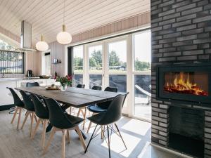 une salle à manger avec une cheminée, une table et des chaises dans l'établissement 10 person holiday home in L kken, à Løkken