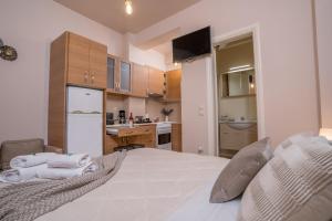 a bedroom with a large white bed and a kitchen at Comfy and Cosy Studio Kalamata in Kalamata