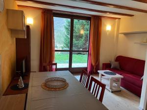 a living room with a table and a red couch at La Casa Bianca - ski, hike & bike in Passo del Tonale