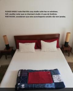a white bed with a red and blue blanket on it at Casa Privada do Plateau in Praia