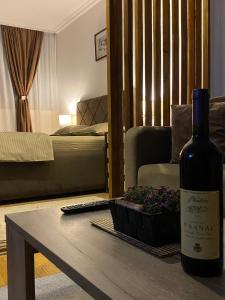 - une bouteille de vin assise sur une table avec une plante dans l'établissement Delta Apartman, à Podgorica