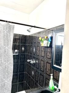 y baño con ducha y azulejos blancos y negros. en Casa Carlota en Tijuana