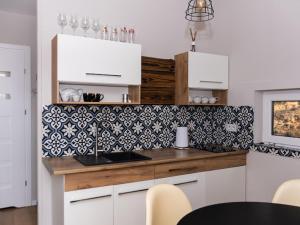 una cocina con armarios blancos y azulejos blancos y negros en Brama Do Lasu - Domek Mocy, en Borków