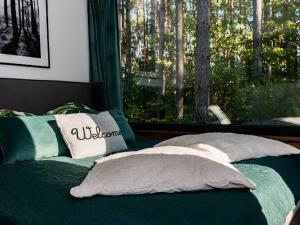 a bed with two pillows in front of a window at Brama Do Lasu - Domek w Koronach Drzew in Kielce