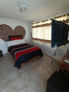 a bedroom with a bed and a flat screen tv at Hotel Fer in San Juan Teotihuacán