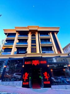 un gran edificio con letreros rojos en la parte delantera en Black House Otel en Ankara