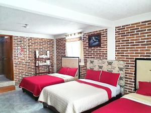 2 camas en una habitación con paredes de ladrillo en Hotel Fer en San Juan Teotihuacan