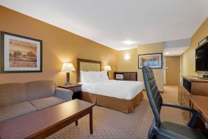 Best Western Plus Emerald Isle Hotel في سيدني: غرفه فندقيه بسرير واريكه
