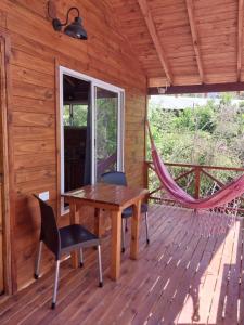 a wooden deck with a hammock and a wooden table and chairs at Cabañas Sidharta in Tigre