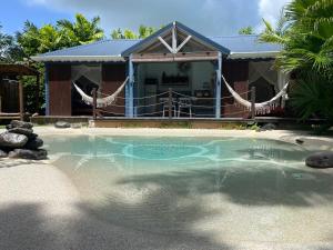 a swimming pool in front of a house at TIKI PARADISE LODGE FWI in Sainte-Anne