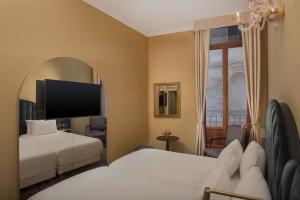 a hotel room with two beds and a flat screen tv at NH Venezia Santa Lucia in Venice